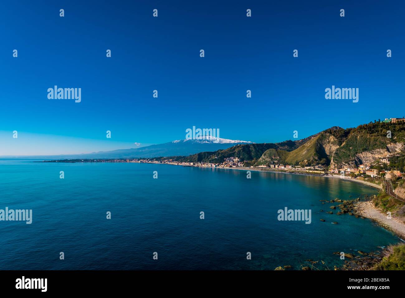 Vue imprenable sur la magnifique montagne enneigée Etna et la baie de Giardini Naxos (première colonie grecque en Sicile), tourné de Capo Taormina, Sicile Banque D'Images