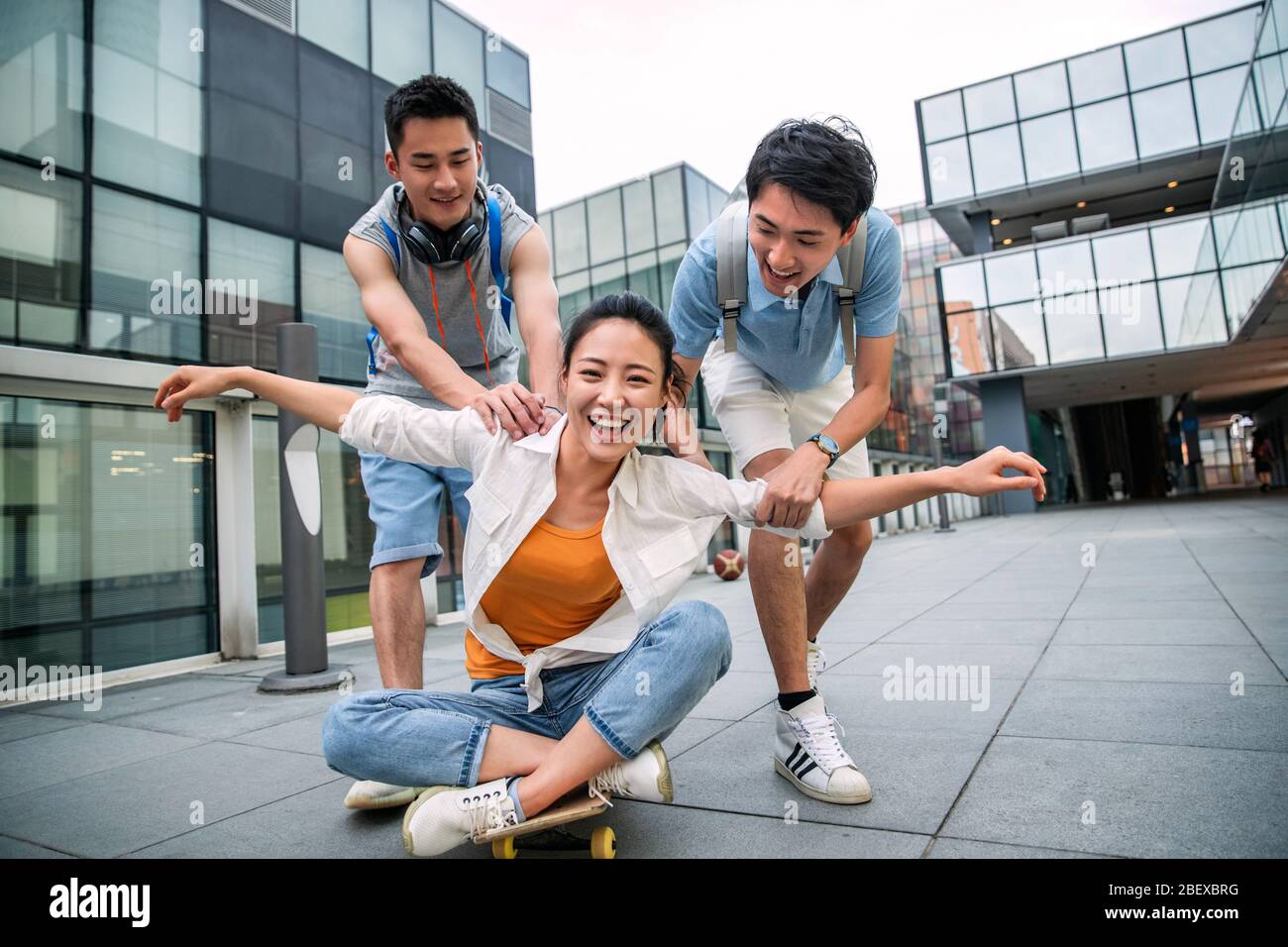 Le jeune homme pousse la femme classmate assis sur un skateboard Banque D'Images