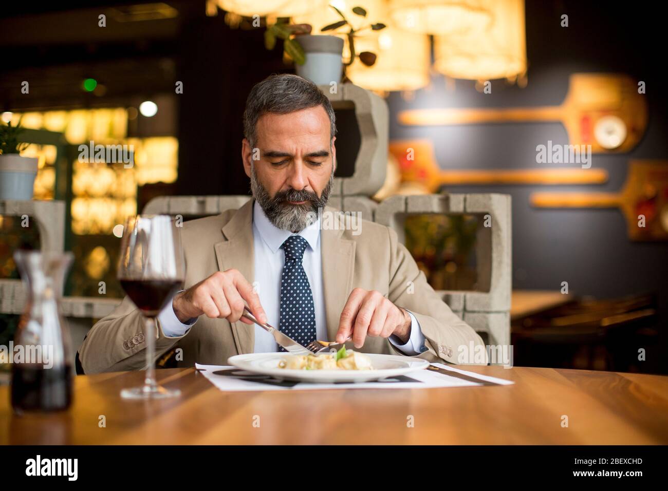 Bel homme mûr buvant du vin rouge pendant le déjeuner au restaurant Banque D'Images