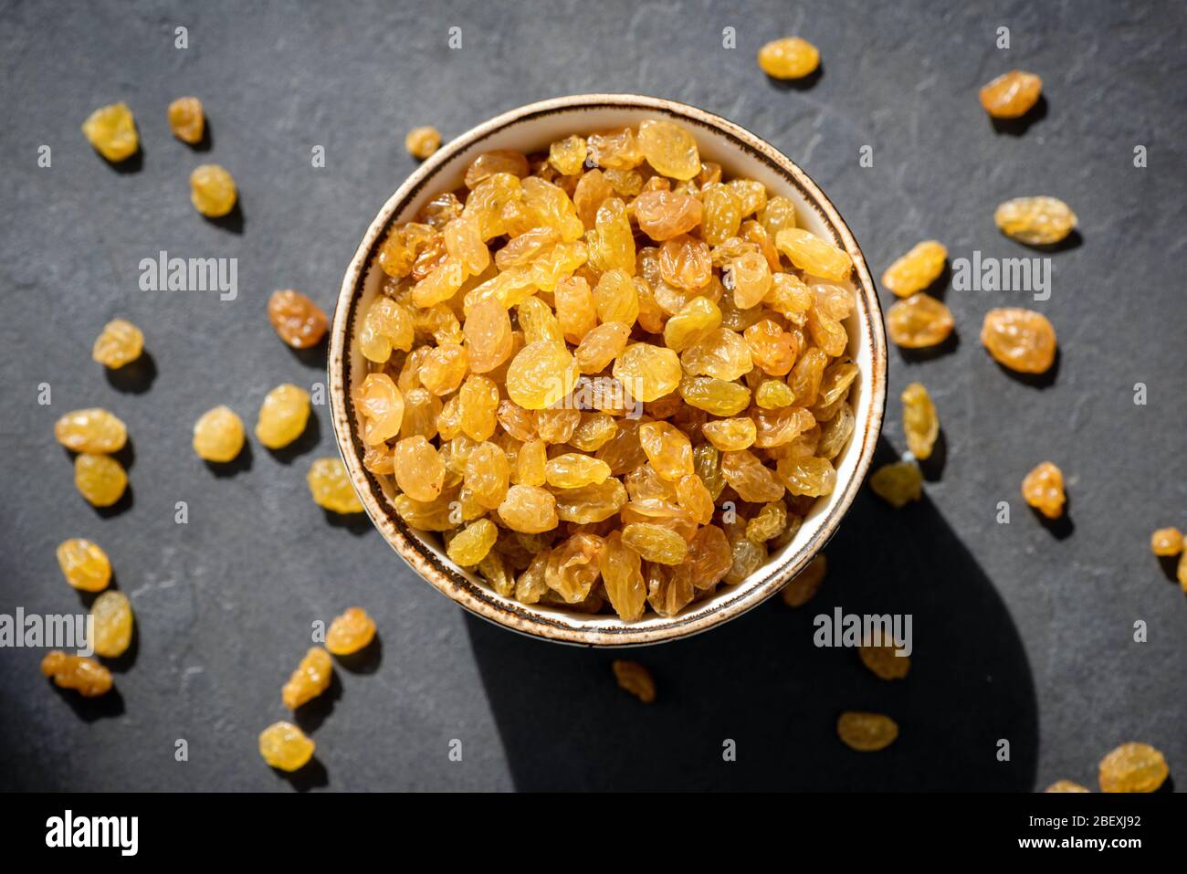 Raisins secs dorés ou sultana dans un bol sur fond noir, vue sur le dessus de table. Fruits secs, encas sains Banque D'Images