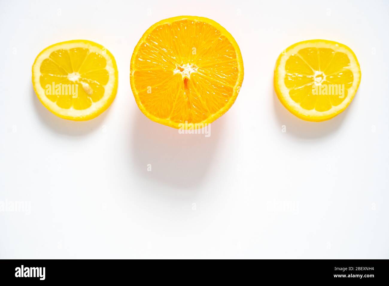 Deux tranches de citron et une tranche d'orange disposées en rangée sur un fond blanc Uni Banque D'Images