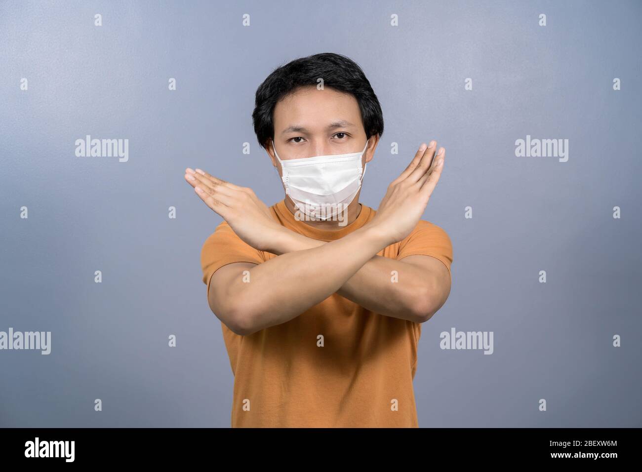 Portrait d'un homme asiatique portant un masque chirurgical face et ne prononcez aucune action pour l'infection du coronavirus sur fond bleu, éclosion de covid19 et pandémie, Banque D'Images