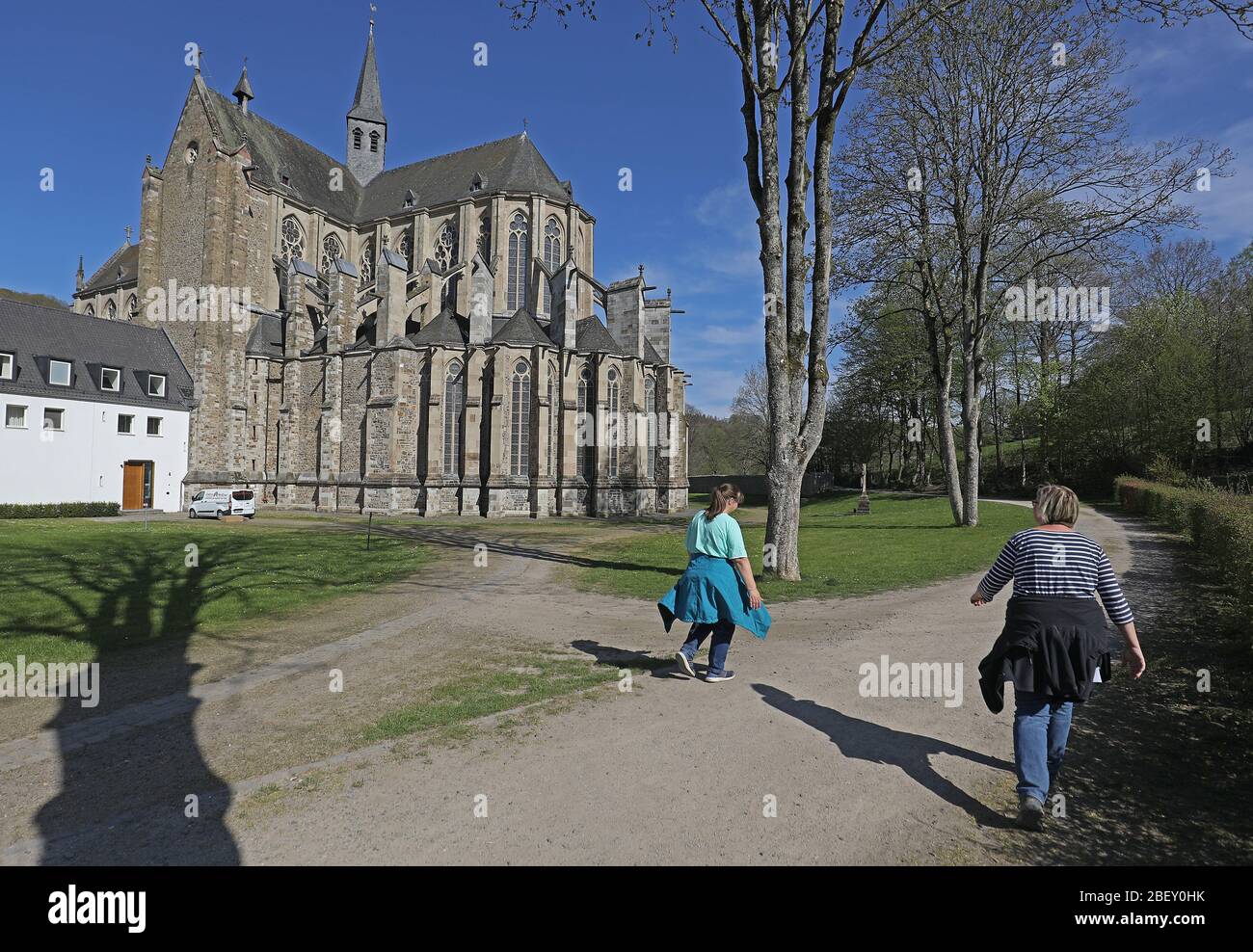 16 avril 2020, Rhénanie-du-Nord-Westphalie, Odenthal: Deux femmes marchent le long de la cathédrale d'Altenberg avec une distance entre elles. En temps de pandémie de corona, le gouvernement du NRW a fait campagne ces derniers jours pour assouplier les restrictions de corona. La plupart d'entre eux resteront en place après tout. Photo: Oliver Berg/dpa Banque D'Images