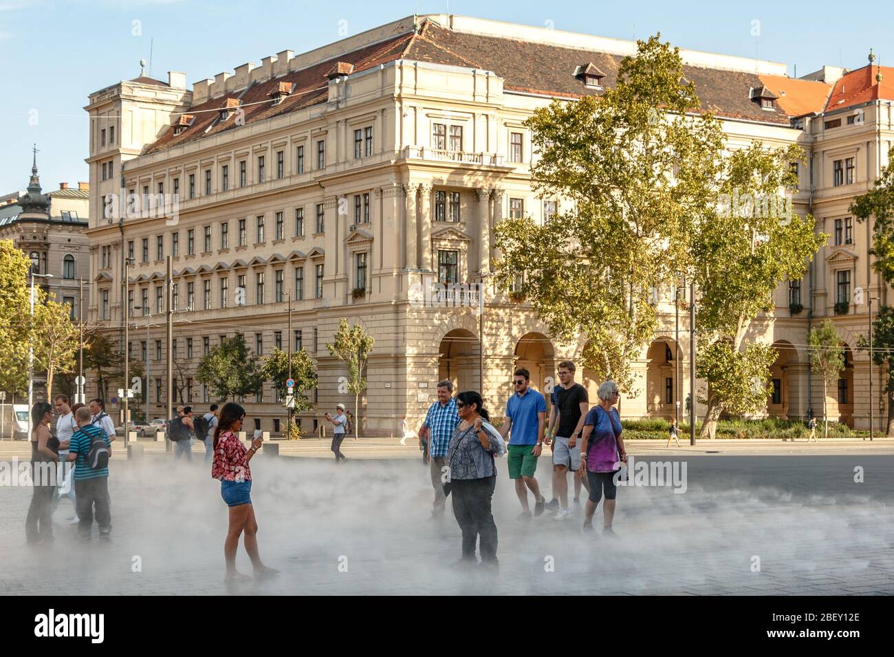 Les touristes se rafraîchissant dans la brume sur la place Kossuth à Budapest, en Hongrie Banque D'Images