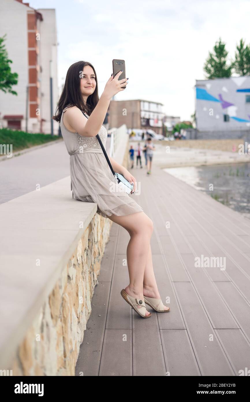 Fille avec téléphone sur la jetée. Jolie fille prenant des selfies dans la ville Banque D'Images