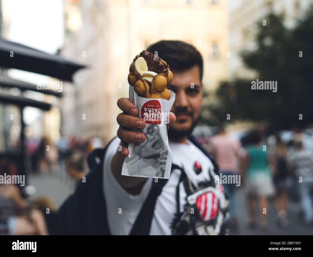 Jeune homme tenant une gaufres à bulles avec crème glacée et chocolat. Gaufre aux fruits, au chocolat et à la glace Banque D'Images