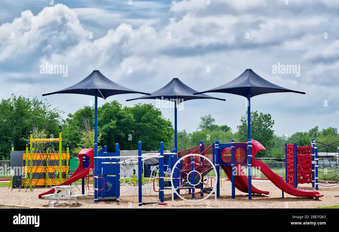Une aire de jeux scolaire publique est désertée pendant la période de quarantaine du coronavirus à Houston, au Texas. Trois parasols se distinguent par le soleil. Banque D'Images