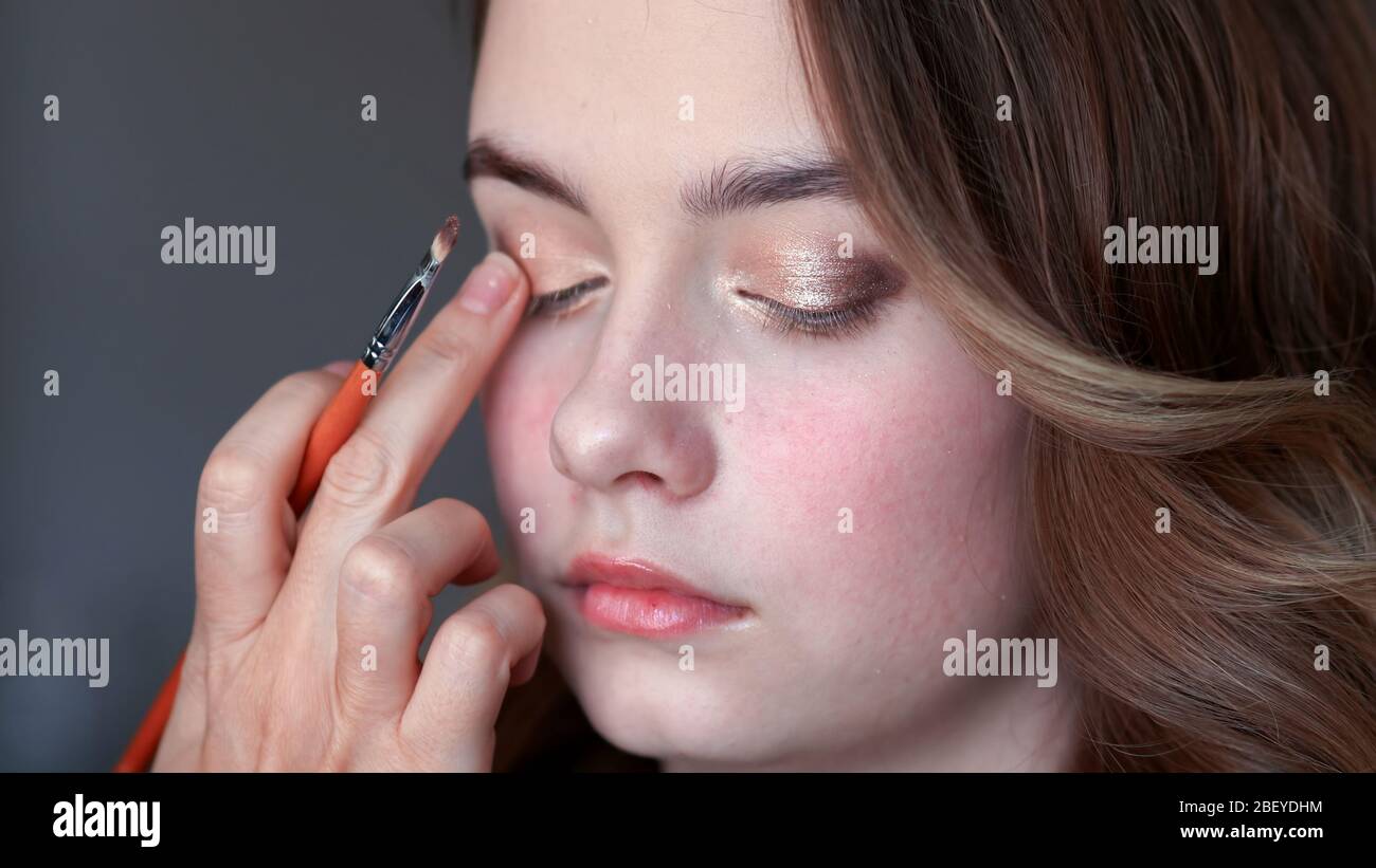 L'artiste de maquillage peint les paupières sur une fille modèle. Banque D'Images