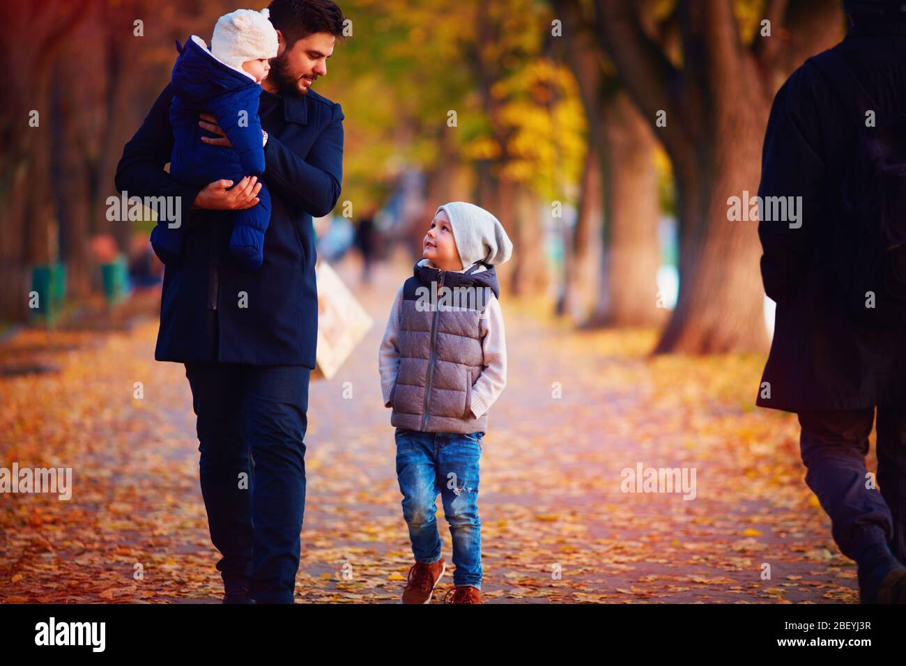 père avec enfants marchant le long de la rue d'automne Banque D'Images