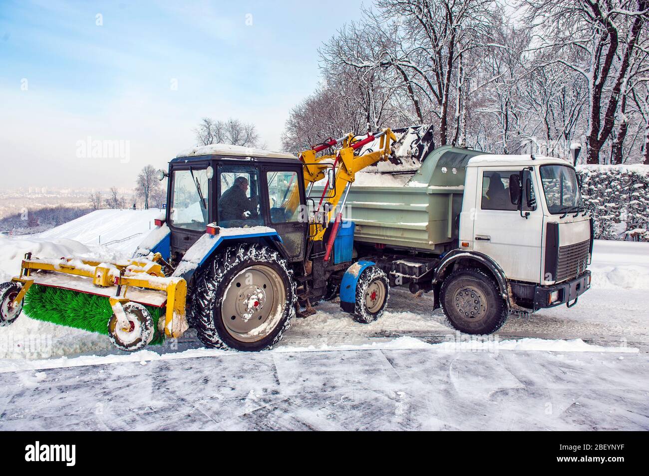 Machine de nettoyage de neige de tracteur déneigeuse chargement de tas de  neige sur un camion de vidage. Chasse-neige à l'extérieur nettoyage de la  ville de la rue après blizzard ou neige
