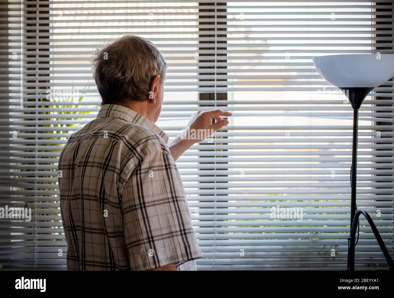 COVID-19 quarantaine de la santé mentale. Homme âgé regardant sur la fenêtre, isolement, solitude, distance sociale Banque D'Images