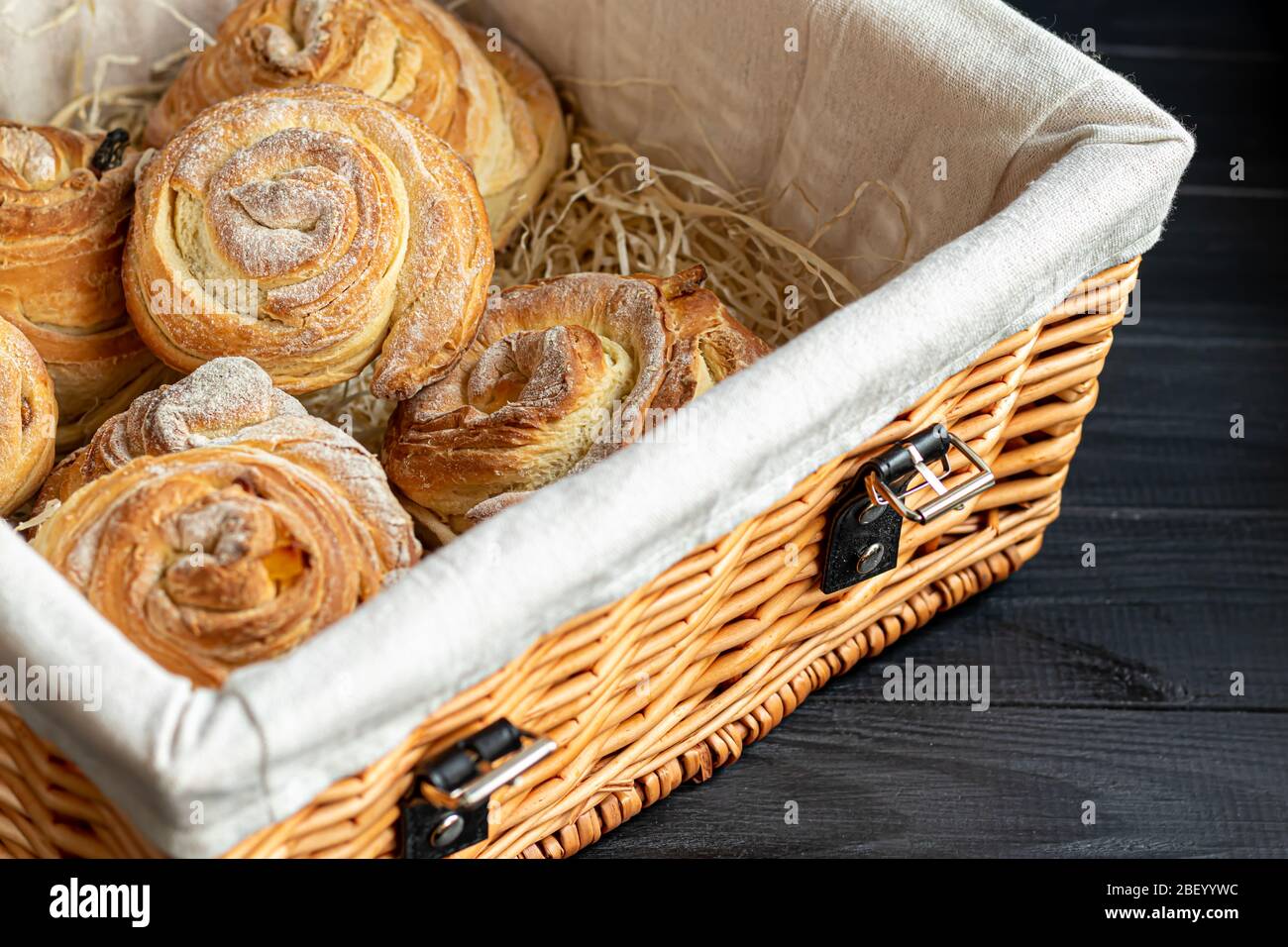Les produits de boulangerie avec raisins secs et fruits secs sont situés sur un fond en bois sombre. Saupoudrés de sucre glace. Kraffins. Cuisine de Pâques. Espace de copie Banque D'Images