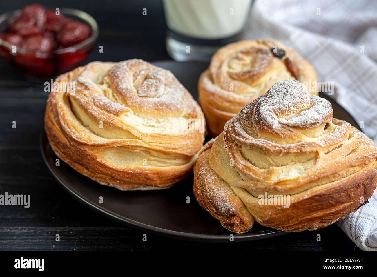 Les produits de boulangerie avec raisins secs et fruits secs sont situés sur un fond en bois sombre. Saupoudrés de sucre glace. Kraffins. Cuisine de Pâques. Espace de copie Banque D'Images