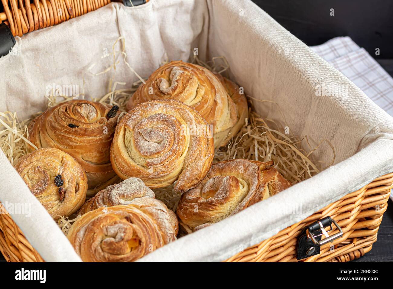 Les produits de boulangerie avec raisins secs et fruits secs sont situés sur un fond en bois sombre. Saupoudrés de sucre glace. Kraffins. Cuisine de Pâques. Espace de copie Banque D'Images