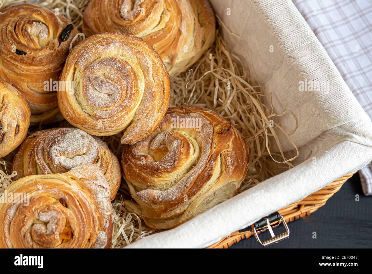 Les produits de boulangerie avec raisins secs et fruits secs sont situés sur un fond en bois sombre. Saupoudrés de sucre glace. Kraffins. Cuisine de Pâques. Espace de copie Banque D'Images