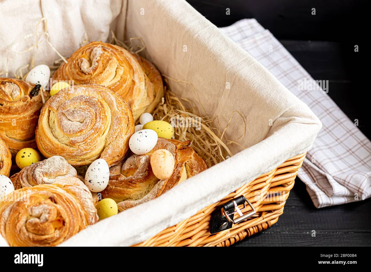 Les produits de boulangerie avec raisins secs et fruits secs sont situés sur un fond en bois sombre. Saupoudrés de sucre glace. Kraffins. Cuisine de Pâques. Espace de copie Banque D'Images
