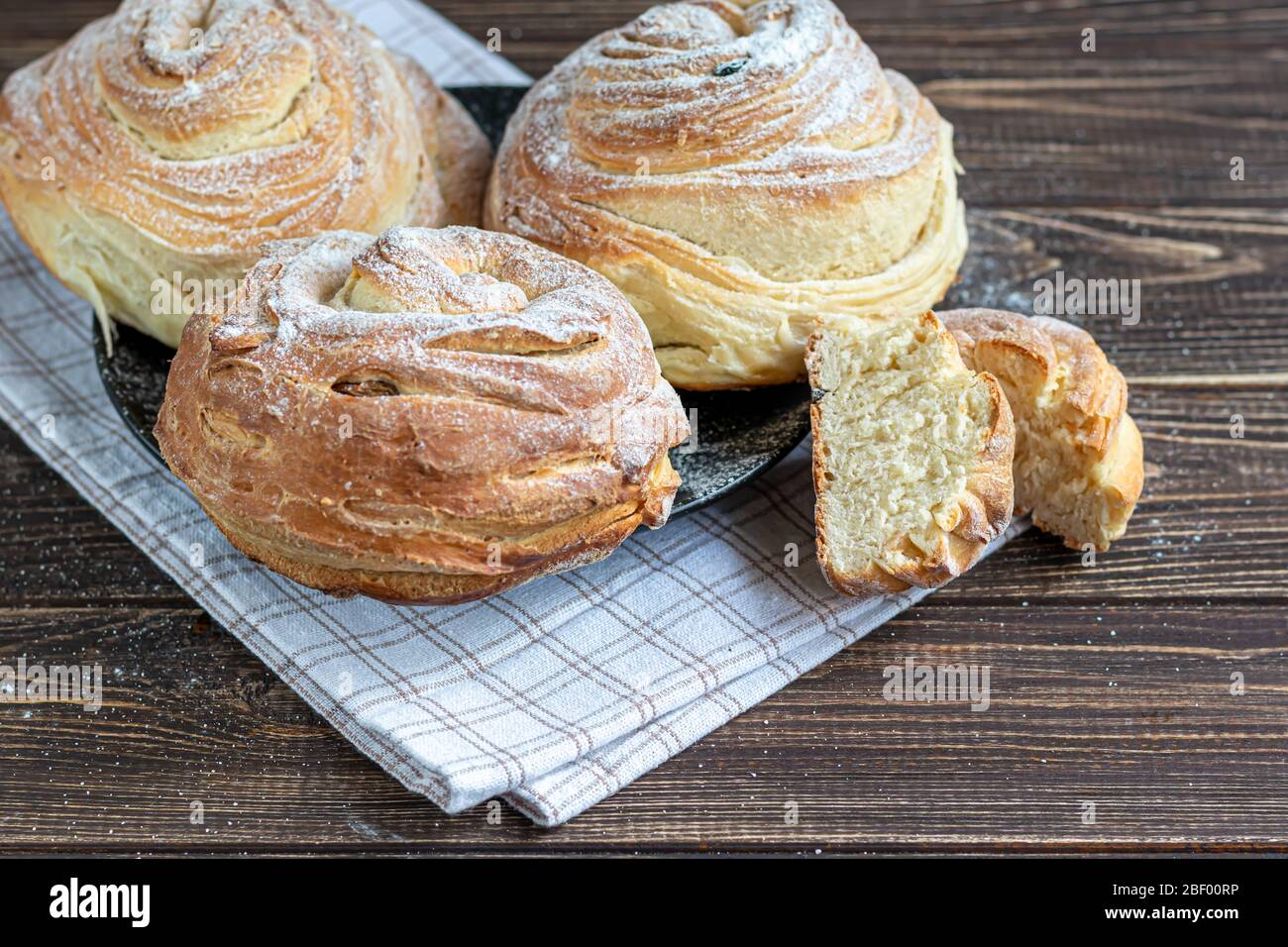 Les produits de boulangerie avec raisins secs et fruits secs sont situés sur un fond en bois sombre. Saupoudrés de sucre glace. Kraffins. Cuisine de Pâques. Espace de copie Banque D'Images