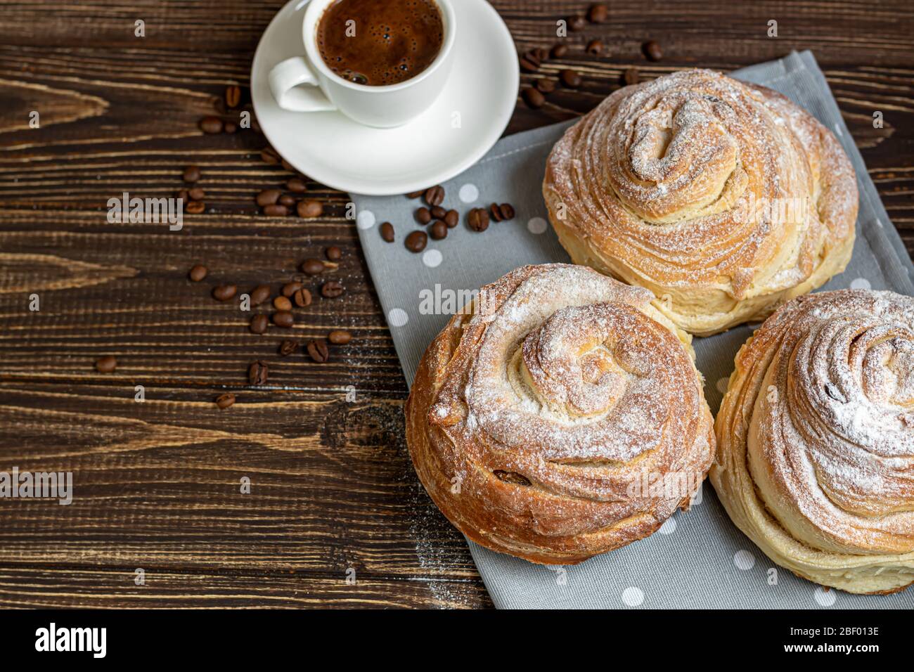 Les produits de boulangerie avec raisins secs et fruits secs sont situés sur un fond en bois sombre. Saupoudrés de sucre glace. Kraffins. Cuisine de Pâques. Espace de copie Banque D'Images