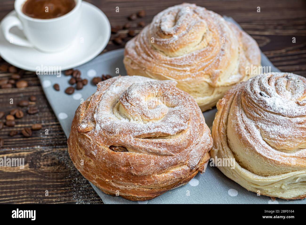 Les produits de boulangerie avec raisins secs et fruits secs sont situés sur un fond en bois sombre. Saupoudrés de sucre glace. Kraffins. Cuisine de Pâques. Espace de copie Banque D'Images