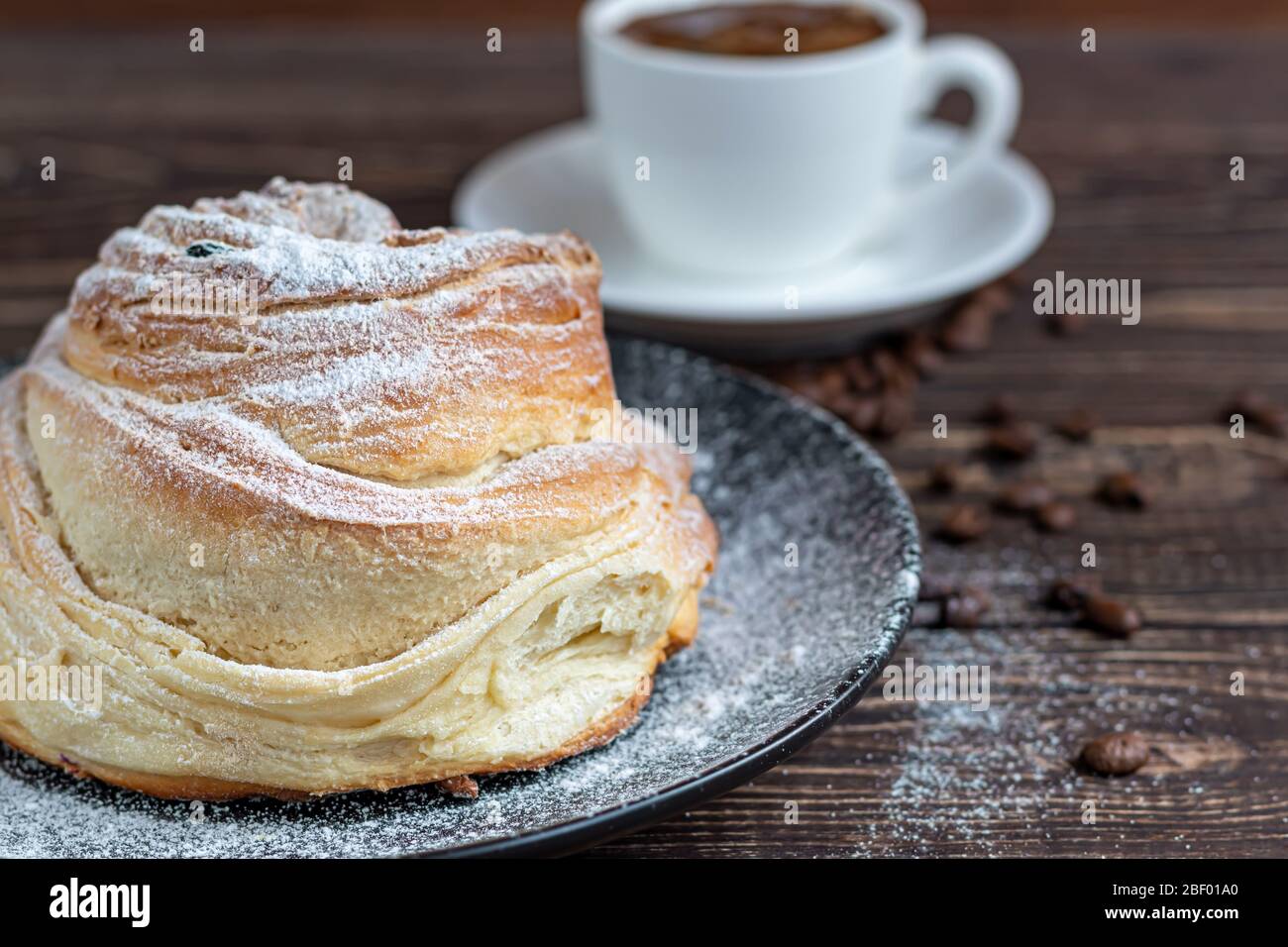 Les produits de boulangerie avec raisins secs et fruits secs sont situés sur un fond en bois sombre. Saupoudrés de sucre glace. Kraffins. Cuisine de Pâques. Espace de copie Banque D'Images