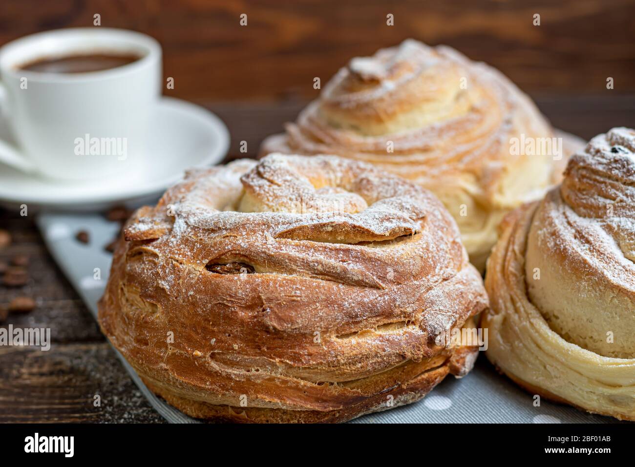 Les produits de boulangerie avec raisins secs et fruits secs sont situés sur un fond en bois sombre. Saupoudrés de sucre glace. Kraffins. Cuisine de Pâques. Espace de copie Banque D'Images