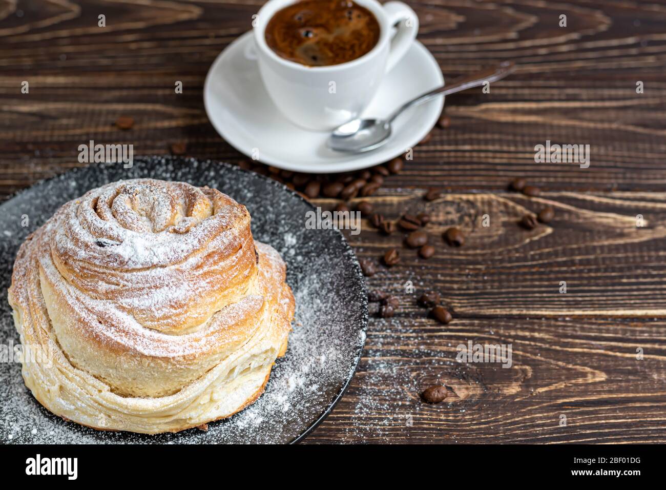 Les produits de boulangerie avec raisins secs et fruits secs sont situés sur un fond en bois sombre. Saupoudrés de sucre glace. Kraffins. Cuisine de Pâques. Espace de copie Banque D'Images