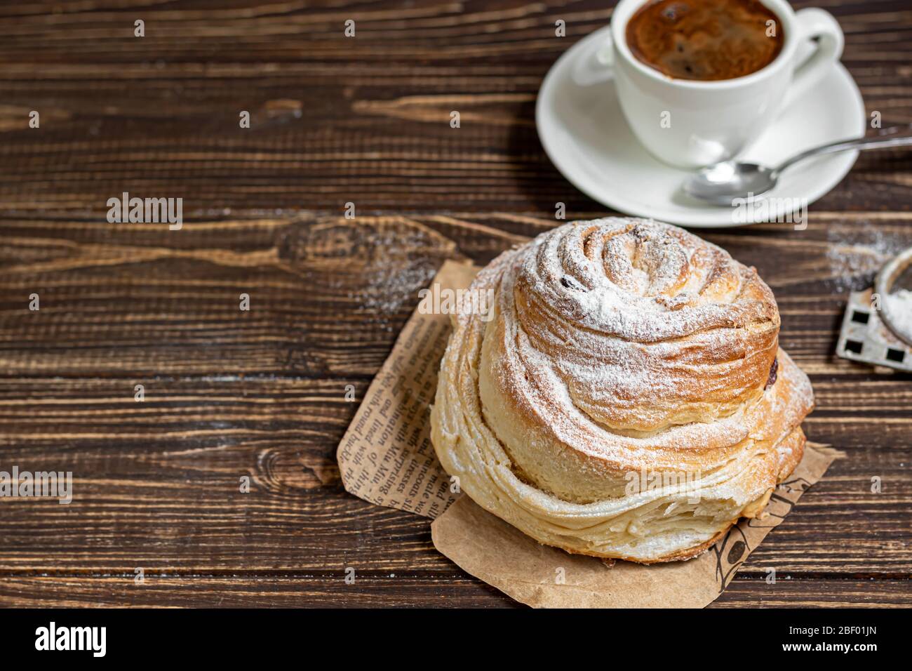 Les produits de boulangerie avec raisins secs et fruits secs sont situés sur un fond en bois sombre. Saupoudrés de sucre glace. Kraffins. Cuisine de Pâques. Espace de copie Banque D'Images