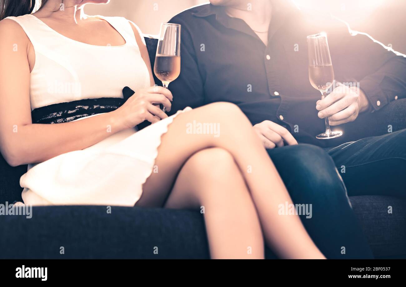 Couple élégant à la date assise sur le canapé à la maison. Soirée romantique avec champagne. Conversation amusante et conversation entre deux amis. Banque D'Images