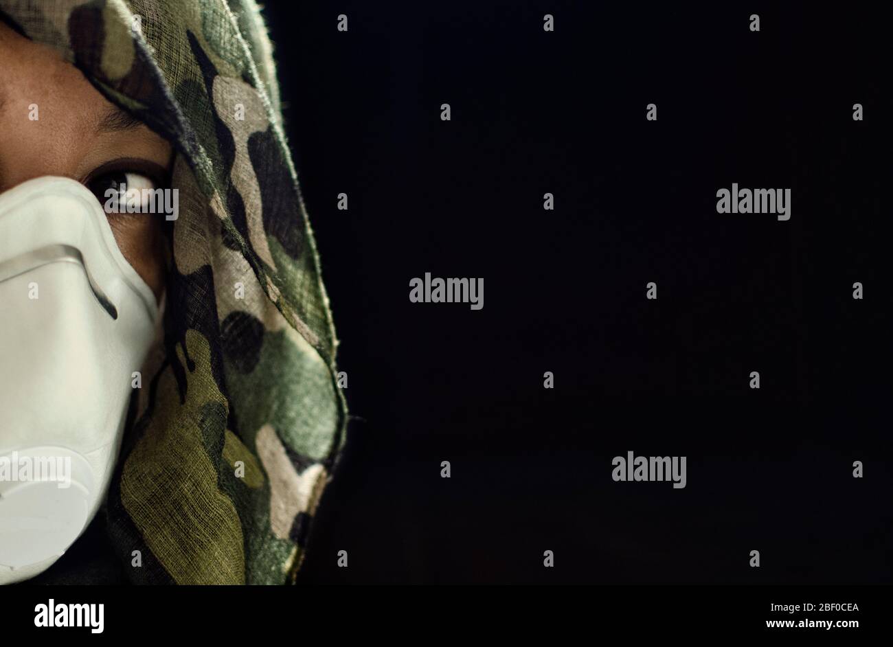 Photo conceptuelle d'une femme guerrière portant un masque FPPP 3 et un casque camouflage. Guerre biologique. Arme létale de coronavirus. Focalisation sélective sur Banque D'Images