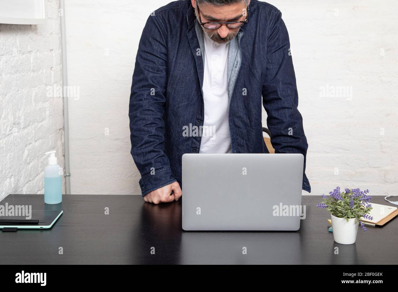 Jeune homme regardant son ordinateur portable à la maison. Travail à la maison concept. Banque D'Images