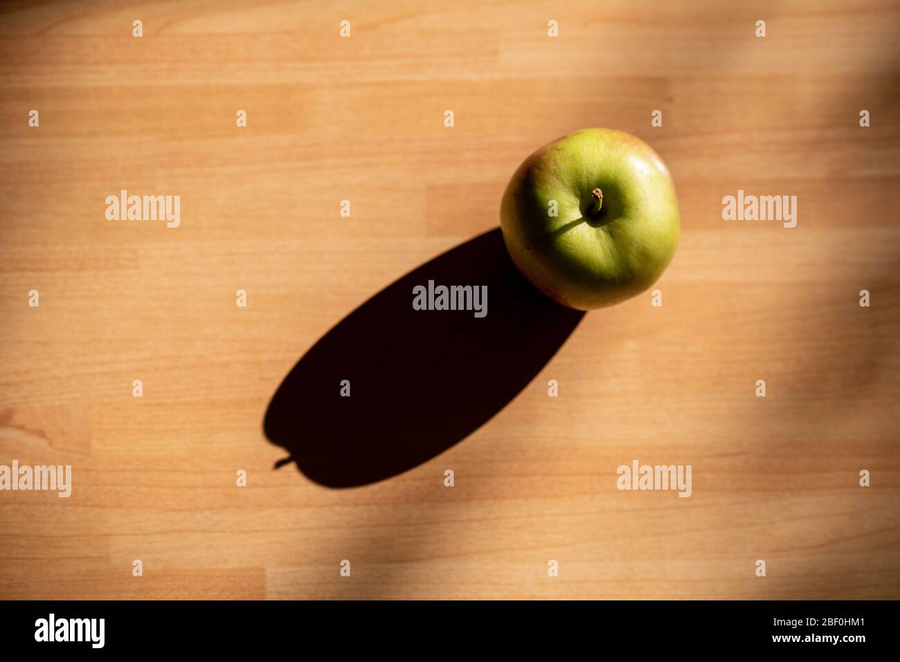 Braeburn pomme sur un panneau en bois avec lumière du soir et ombre Banque D'Images