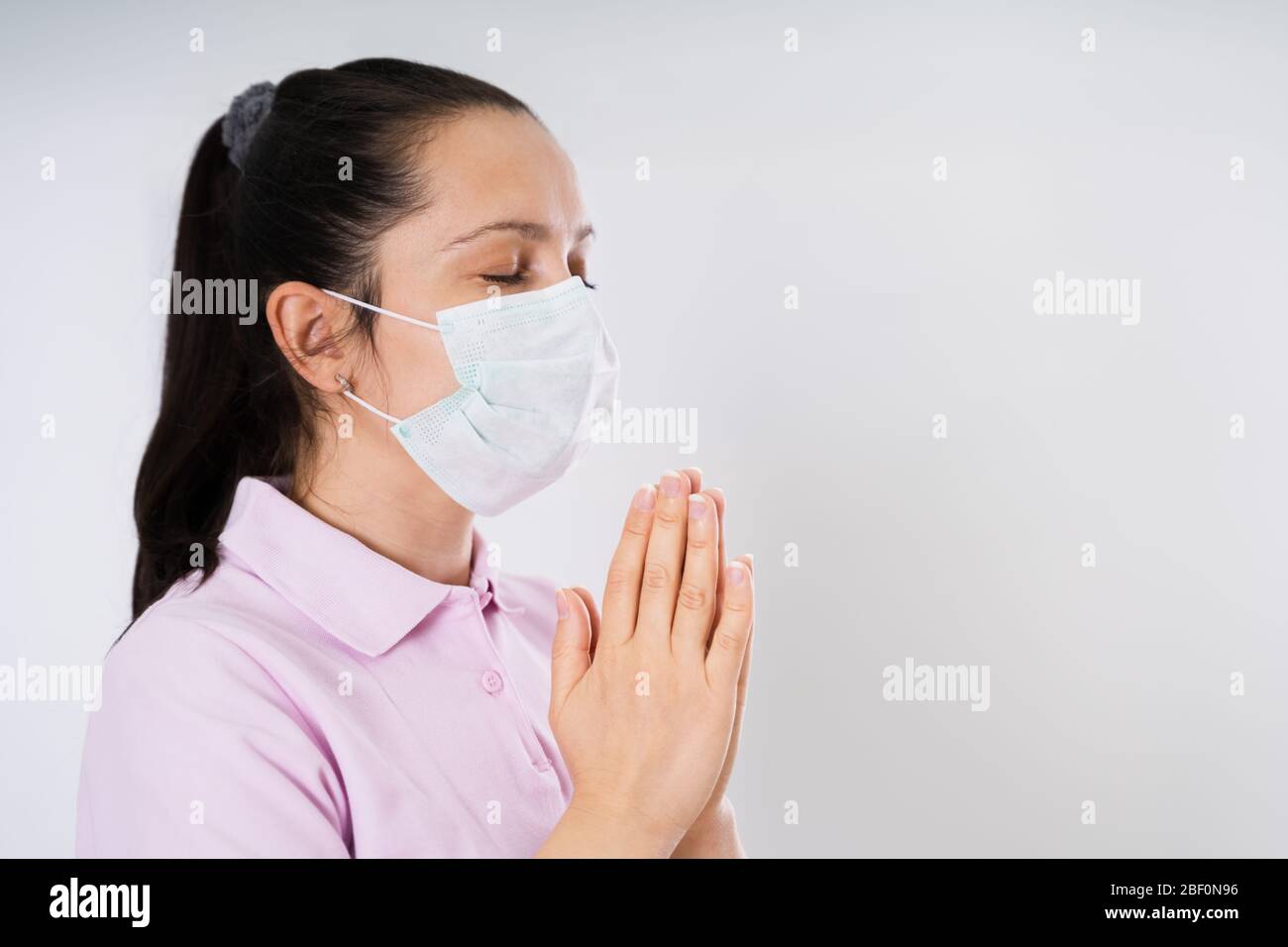 Femme en gants et masque priant pendant une pandémie de coronavirus Banque D'Images