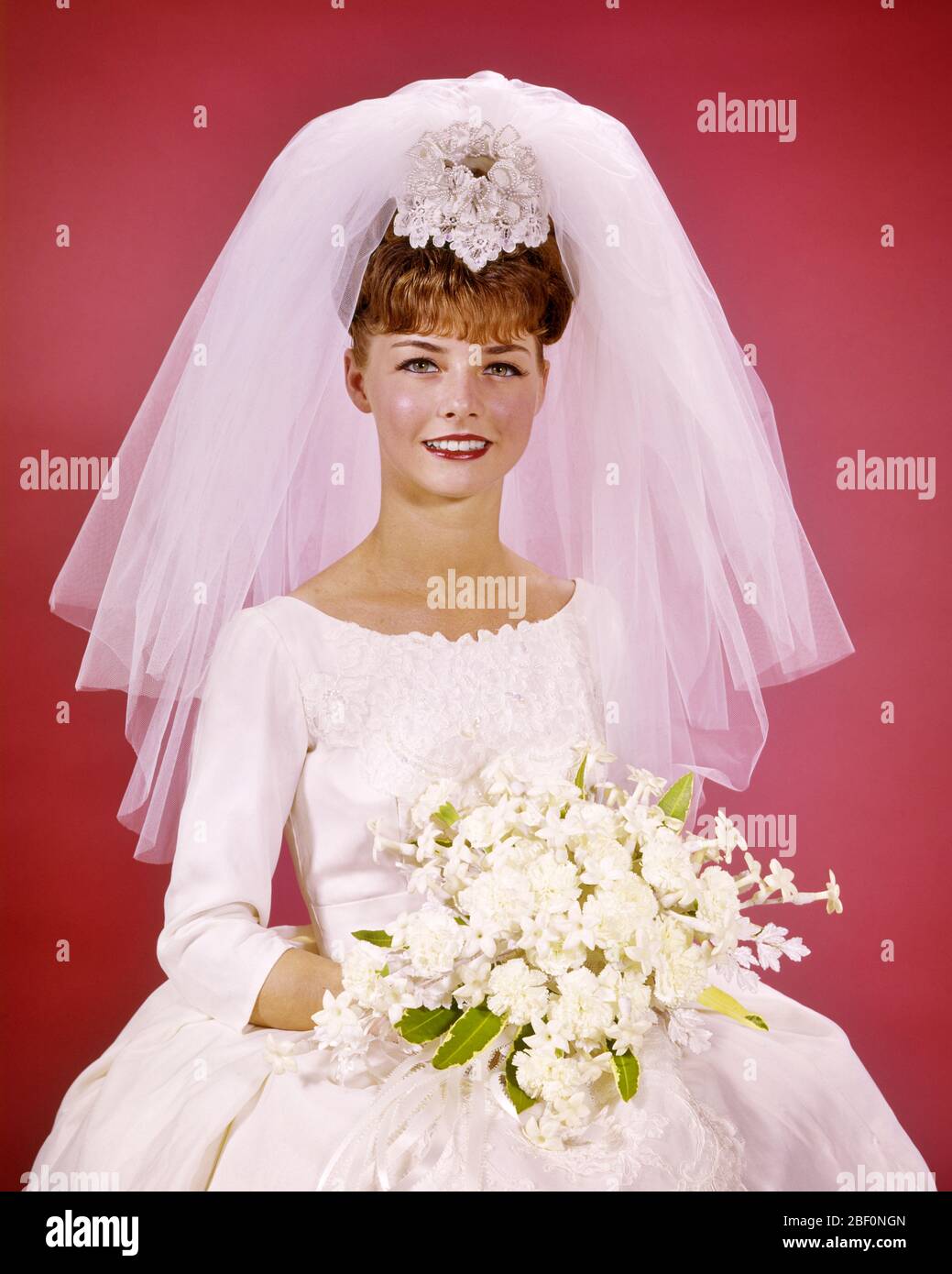 ANNÉES 60 SOURIRE HEUREUX MARIÉE PORTRAIT ASSIS ROBE DE MARIAGE BLANCHE  MARIÉE BOUQUET FLEURS COURT NET VOILE REGARDANT LA CAMÉRA - KB5261 HAR001  HARS STUDIO TOURNÉ GROGNUP SANTÉ ACCUEIL VIE ASSIS COPIE