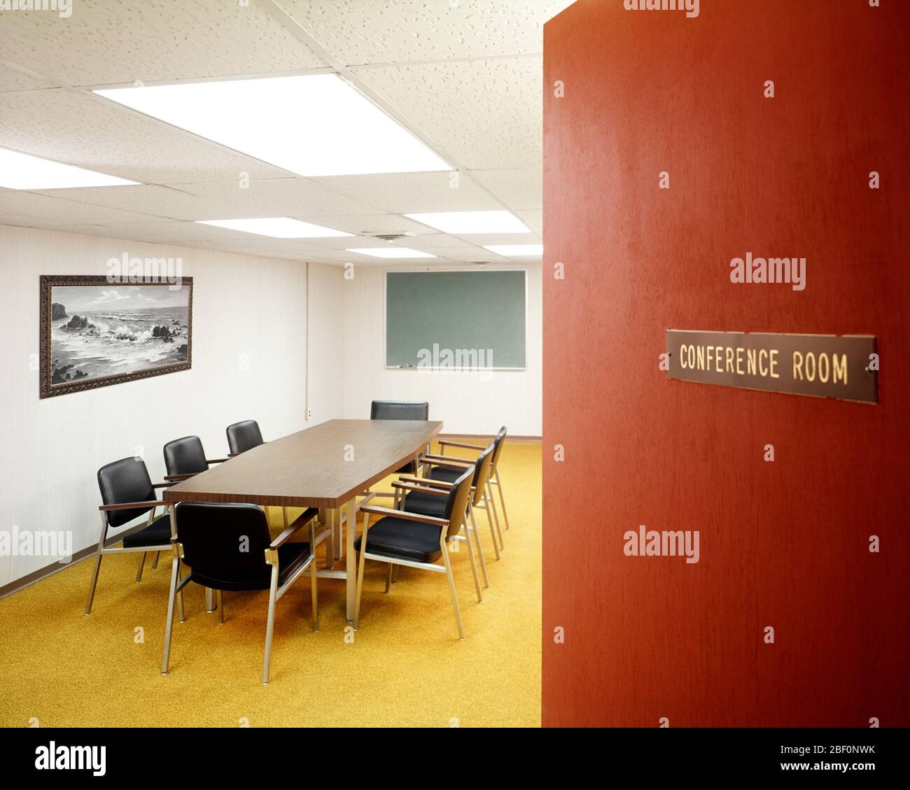 ANNÉES 1970 ESPACE DE TRAVAIL PORTE ENTROUVERTE AVEC VUE SUR VIDE SALLE DE CONFÉRENCE AVEC TABLE LONGUE 8 CHAISES ET TABLEAU VERT À LA FIN DE LA CHAMBRE - KI2394 HAR001 HARS AJAR ENTREPRISE DESIGN INTÉRIEUR ÉLÉGANT HUIT IDÉES DE DÉCORATION MAISON MOBILIER HAR001 À L'ANCIENNE Banque D'Images