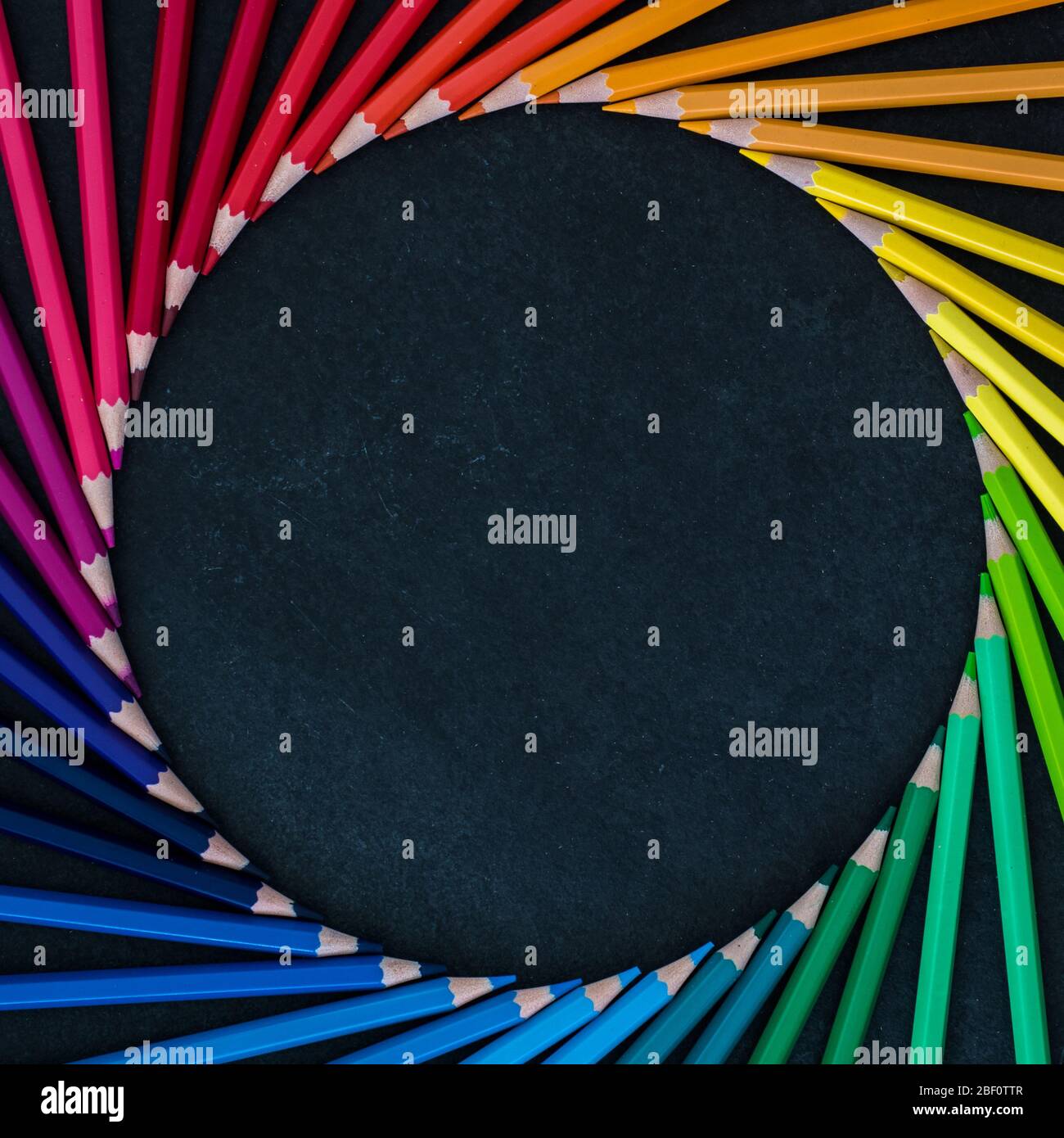 Jeu de crayons de couleur disposés en roue sur fond d'ardoise. Vue de dessus Banque D'Images
