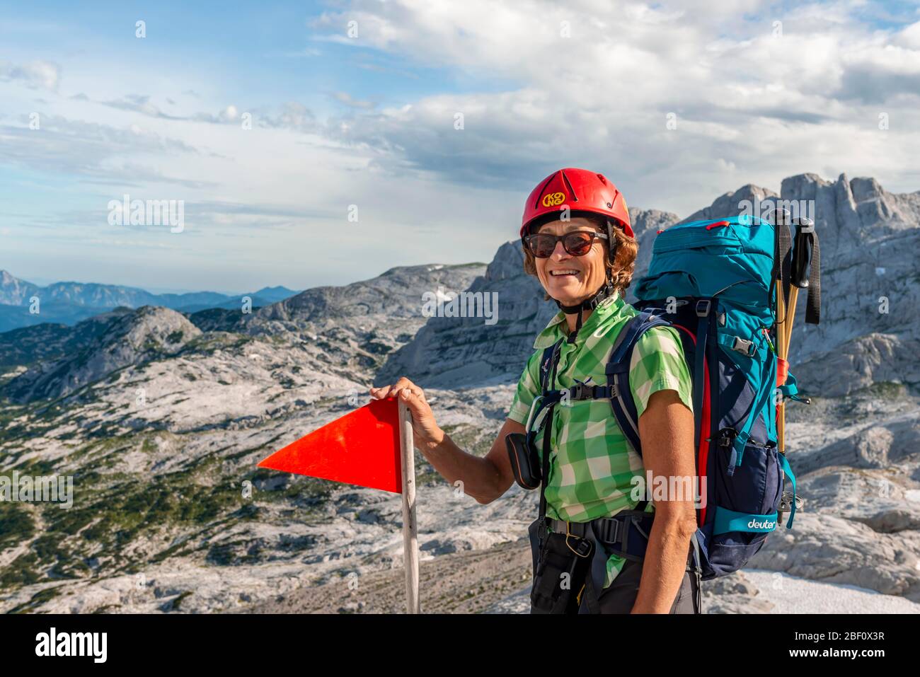 Mountaineer avec sac à dos et casque semble heureux dans la caméra, route de Simonyhuette à Adamekhuette, terrain alpin rocheux, Salzkammergut Banque D'Images