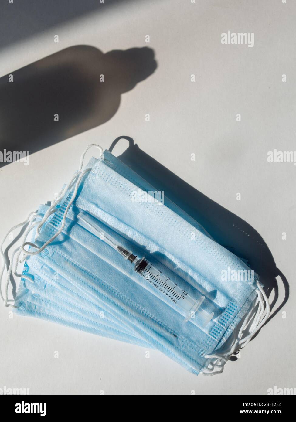 Seringue avec vaccin bleu et ampoule sur le masque médical. Fond blanc Banque D'Images