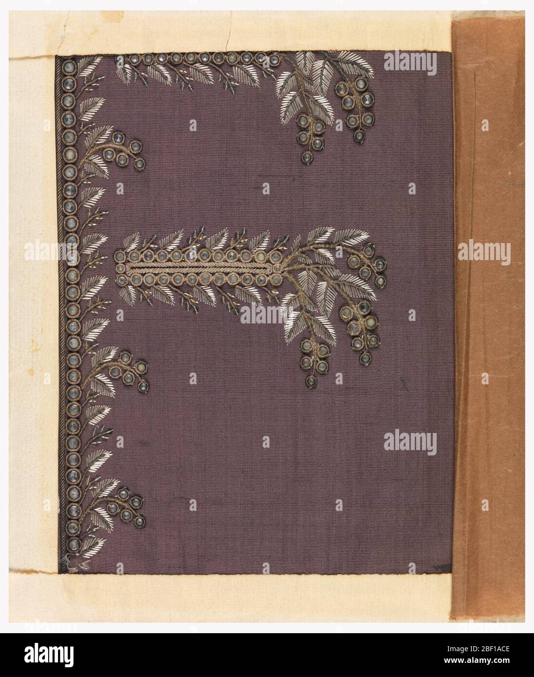 Échantillon de broderie. Motif foliaire formel, brodé avec soie blanche, fil d'argent et paillettes et verre sur une terre de taffeta pourpre. Banque D'Images