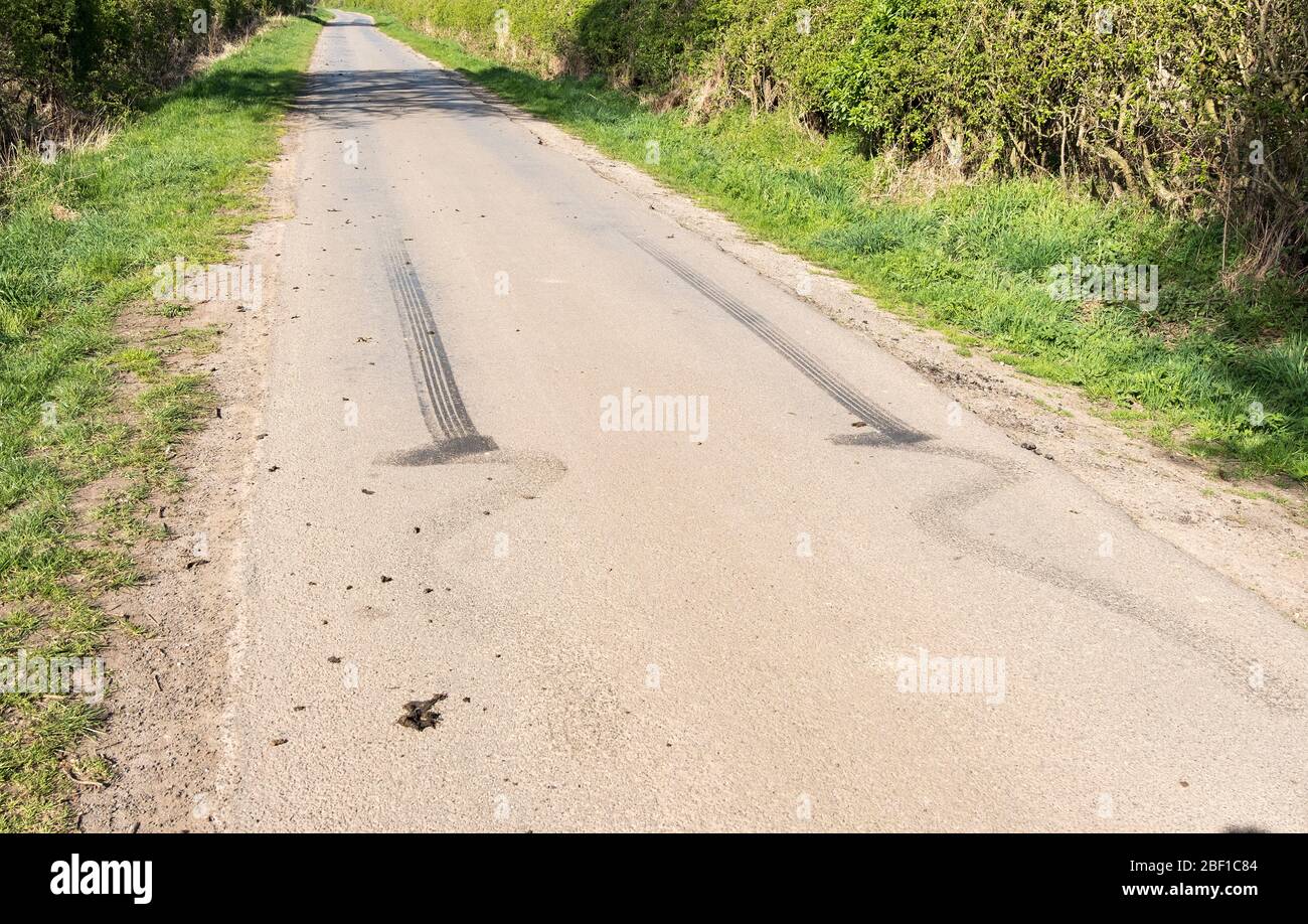 Marques de patins de pneu en caoutchouc noir sur une voie de pays Banque D'Images