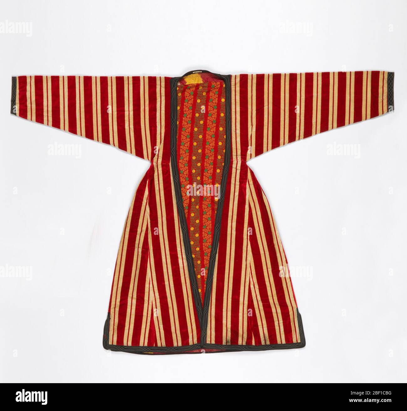 Peignoir. Robe en velours à rayures rouges et blanches avec jupe complète plissée à la taille étroite et manches profondes se serrant au poignet. Bordure en coton noir sergé cousu à la machine en bleu clair et blanc. Banque D'Images