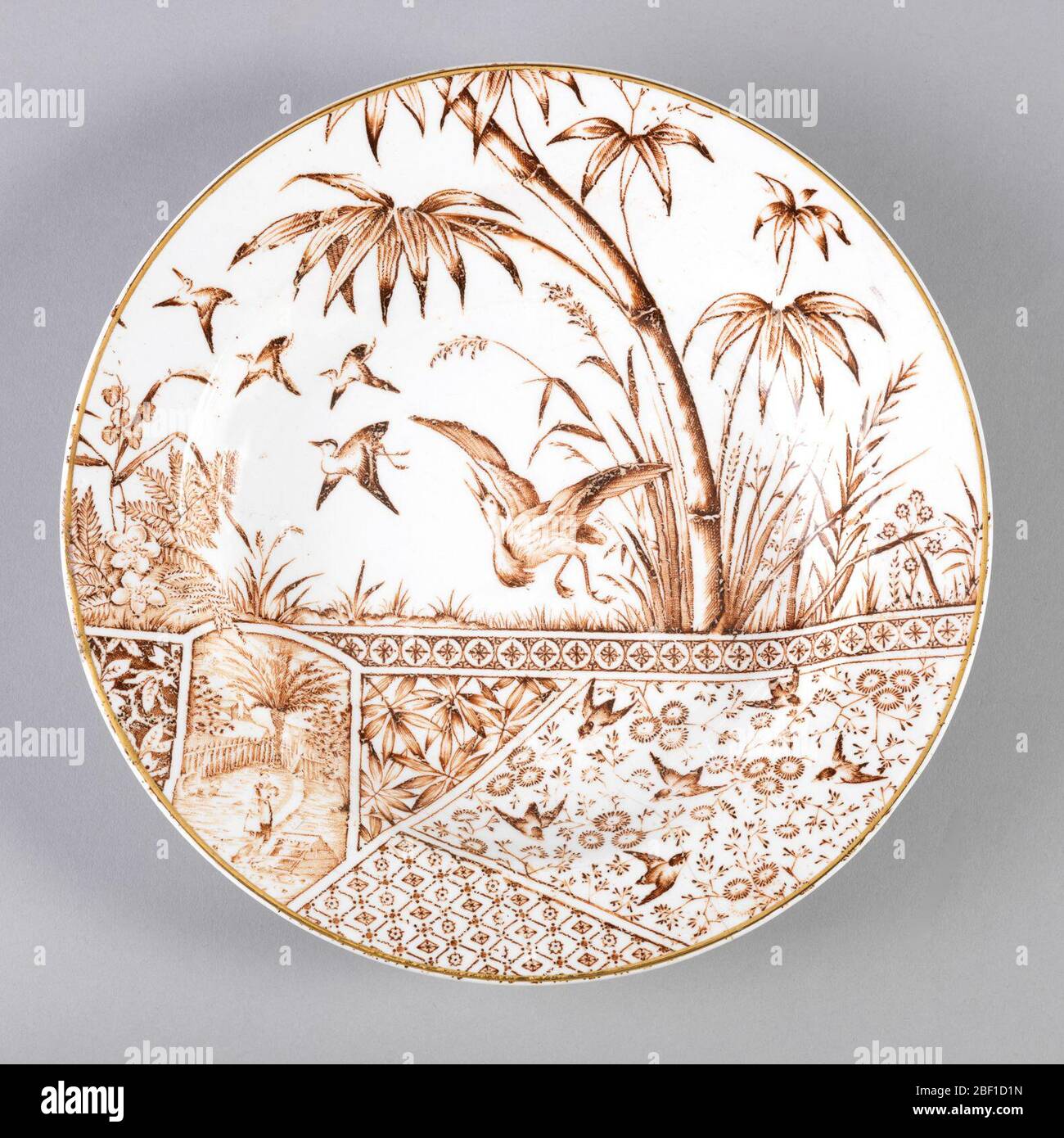 Tropiques. Circulaire, le sol blanc avec la décoration marron à imprimé transfert, la partie supérieure montrant des oiseaux (grues?) En vol dans un paysage, la partie inférieure composée de panneaux de motifs d'inspiration japonaise de forme différente, y compris des fleurs, des oiseaux et geomet Banque D'Images