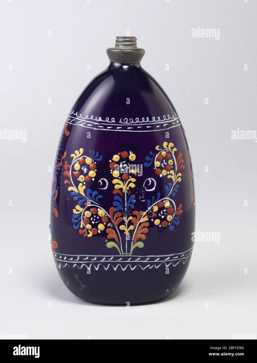 Bouteille. Verre en forme de goutte d'eau, violet foncé, avec décoration peinte. Banque D'Images