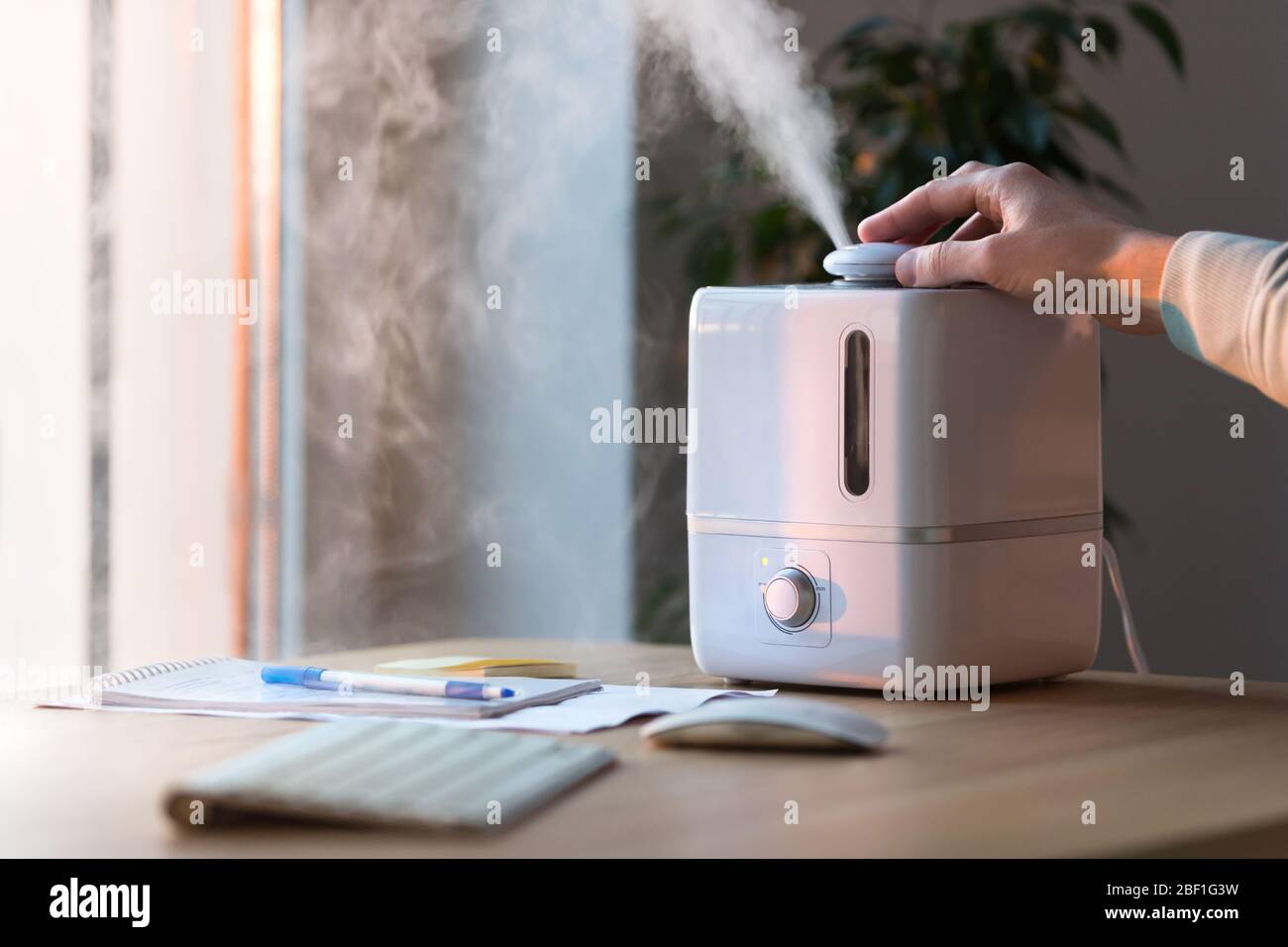 Homme utilisant diffuseur d'huile d'arôme sur la table, vapeur de l'humidificateur, mise au point sélective. Humidification de l'air dans l'appartement pendant la période de l'auto-est Banque D'Images