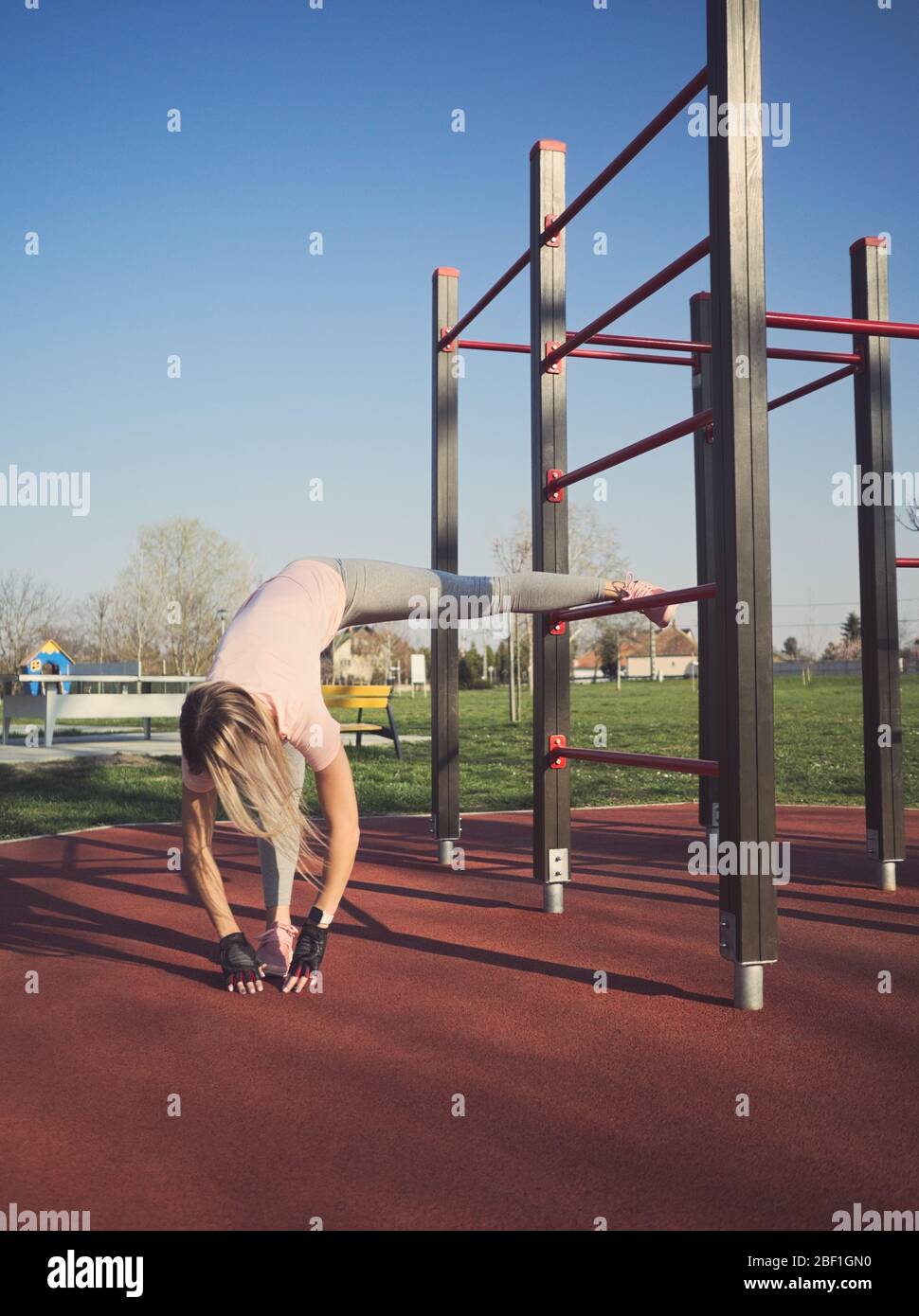 Jeune femme athlétique étirant les jambes sur les barres murales dans le parc Banque D'Images