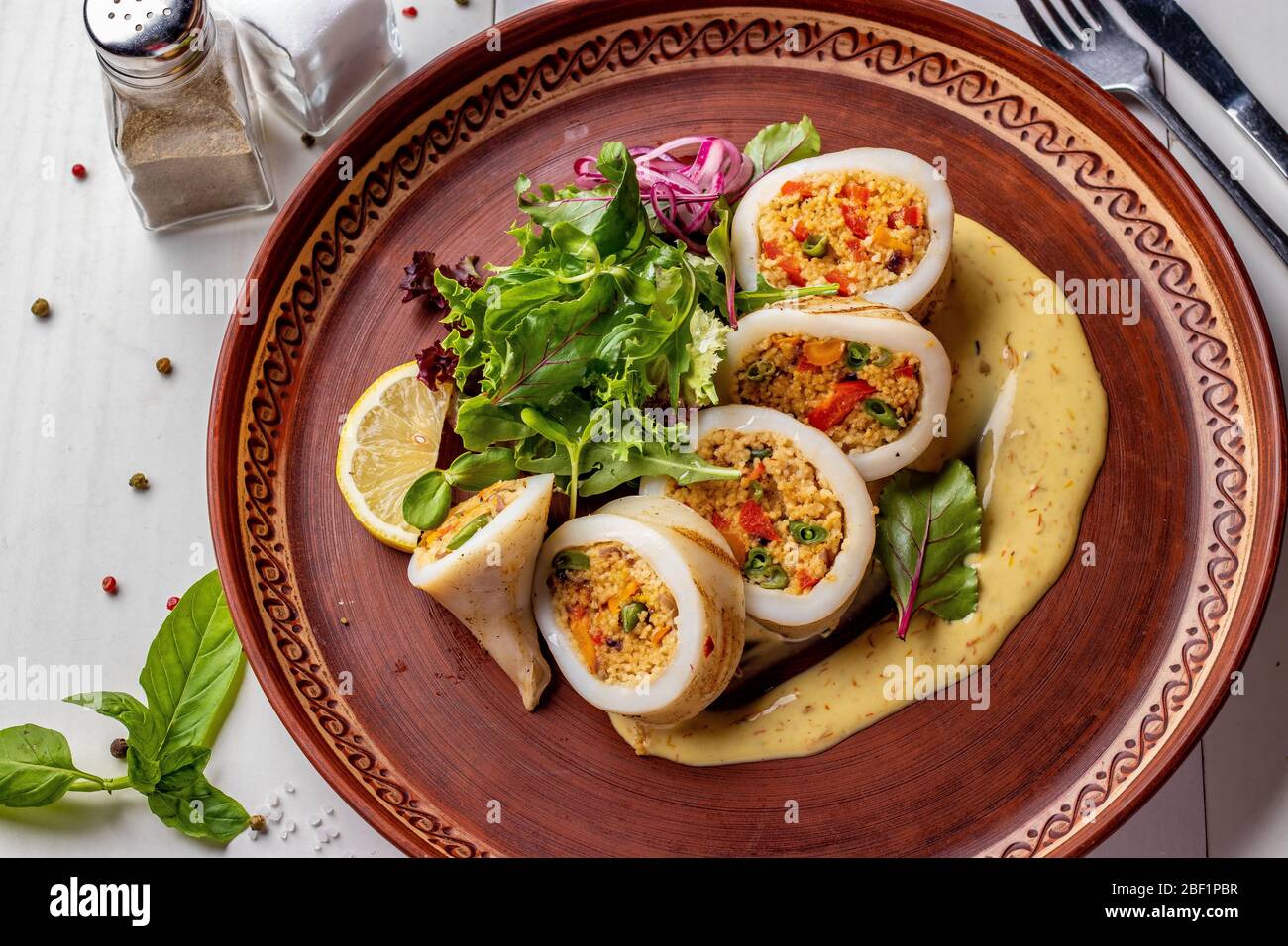 Calmar farci de couscous et légumes servis avec sauce et salade verte, gros plan, menu Restaurant, format horizontal Banque D'Images