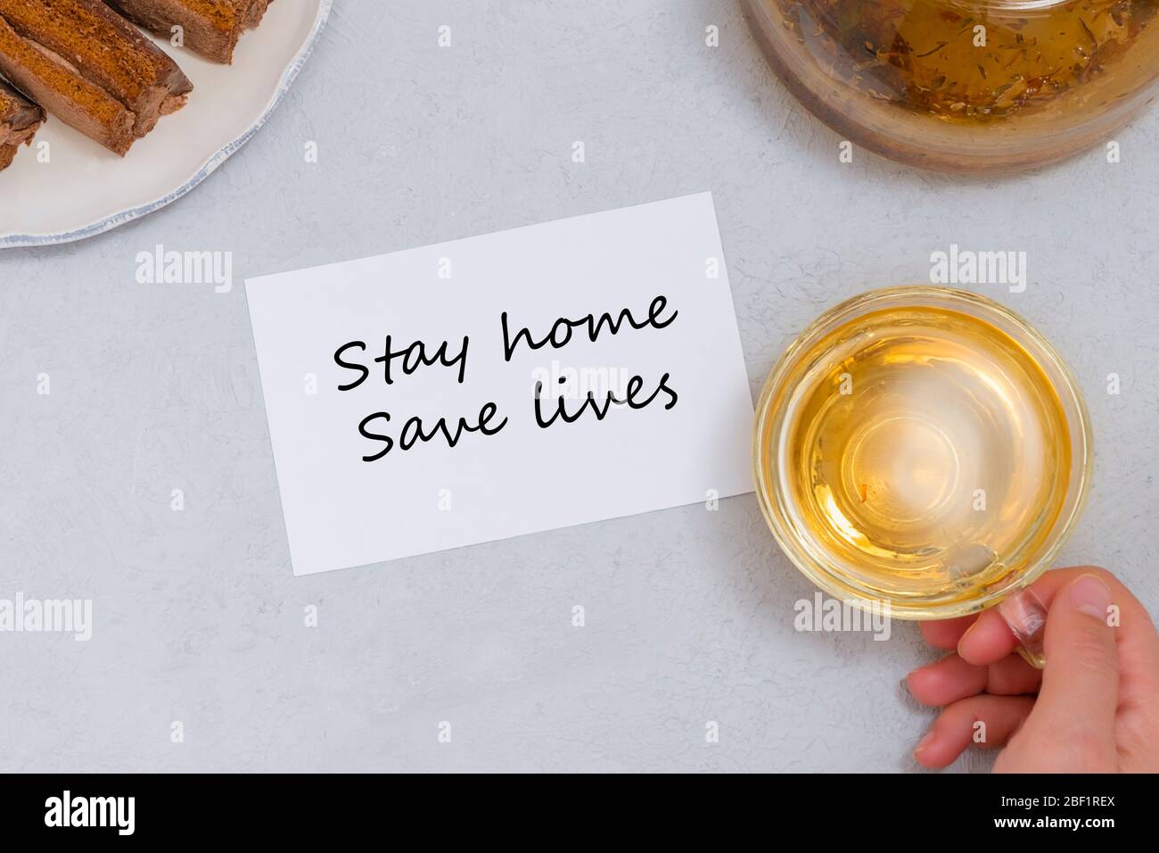 Restez chez vous, sauvez des vies motivation phrase sur note blanche avec thé et bonbons. Motivation d'auto-isolation Banque D'Images