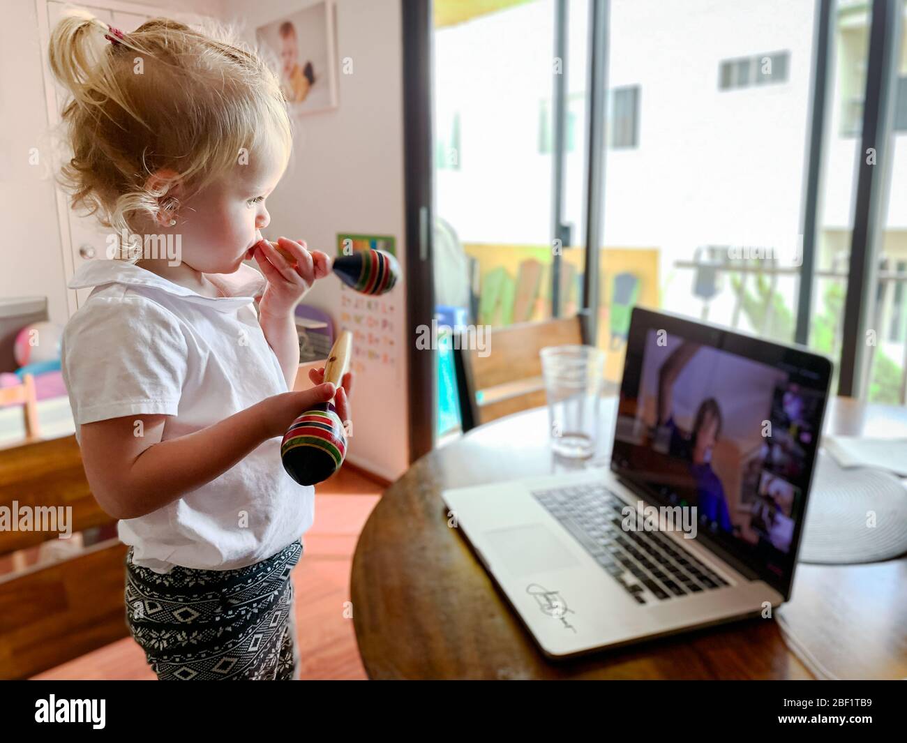 Jolie fille de 21 mois, elle prend sa classe musicale de chez elle via Zoom pendant la quarantaine. Banque D'Images