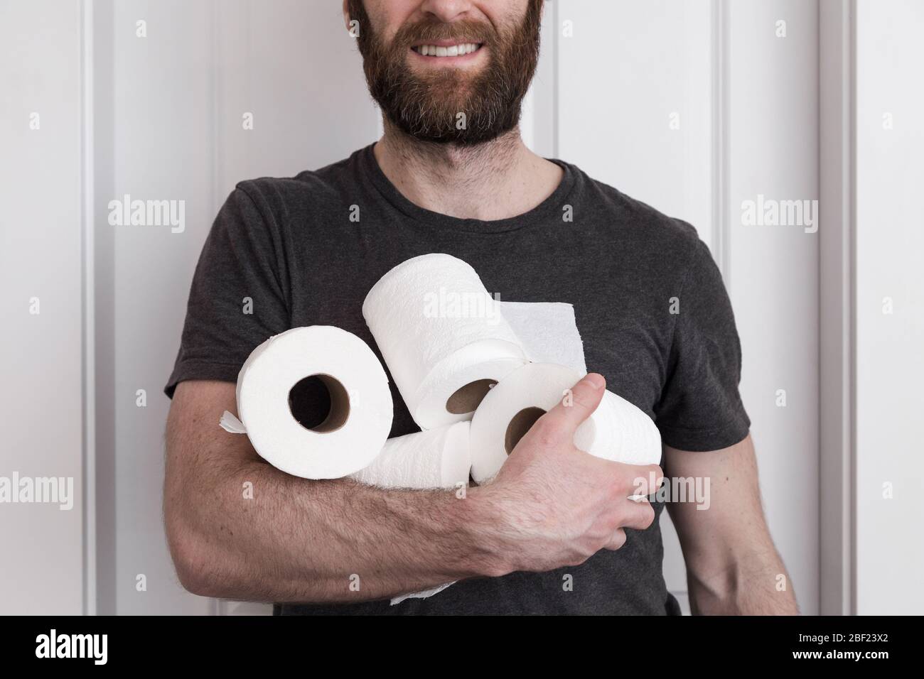 Un homme caucasien souriant tenant des rouleaux de papier toilette le il a monté à bord. Banque D'Images