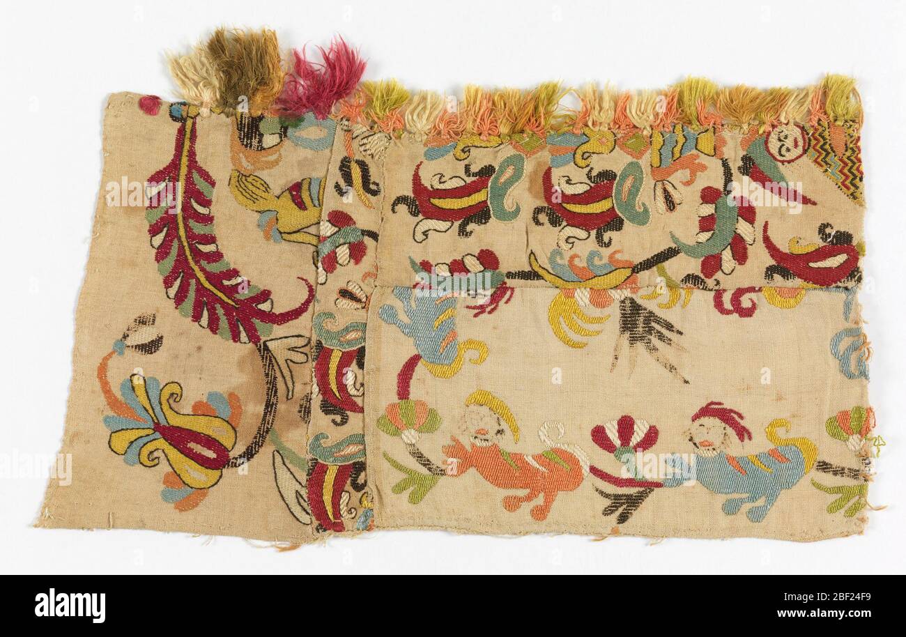 Fragment. Fragment montrant des animaux fantastiques, des fleurs et une figure humaine dans la soie multicolore sur un sol naturel. Banque D'Images