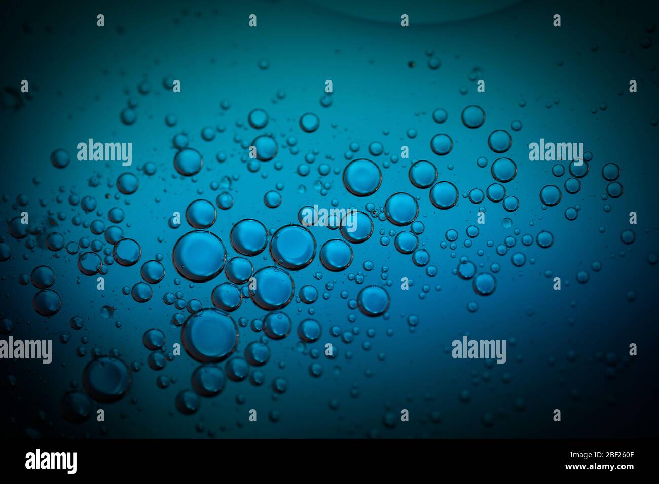 Motif géométrique de gouttelettes d'eau dans un liquide bleu. Les formes sphériques transparentes sont rapprochées. Motifs et textures de bulles de macro. Banque D'Images